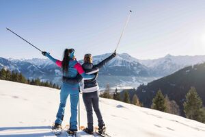 Zwei Frauen posieren im Schnee mit Skistöcken und genießen die Aussicht auf die Berge. | © mr-offenblende.at