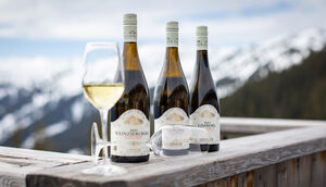 Drei Flaschen Weißwein und ein Weißweinglas auf einem Holztisch in den Bergen. | © Nikolaus Faistauer Photography