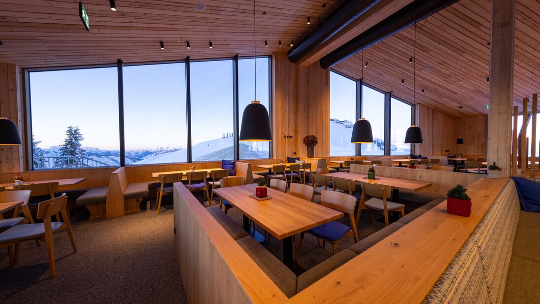 Interior view of mountain restaurant Das Panorama with large windows and wooden decor. | © Nikolaus Faistauer Photography