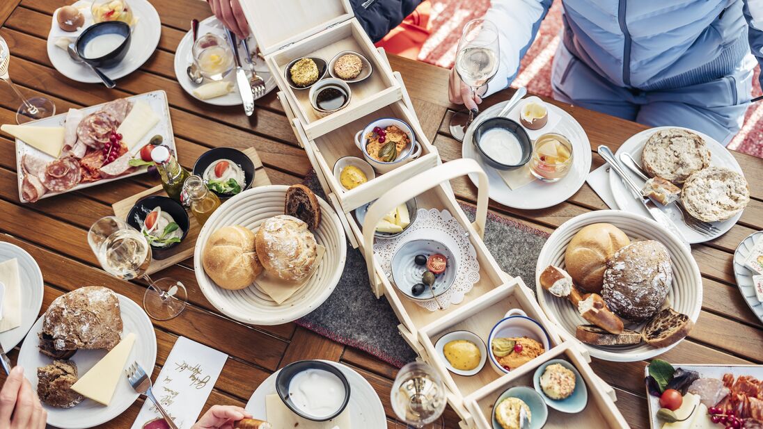 A rich breakfast spread at the mountain restaurant, featuring bread, cheese, cold cuts, and various dips. | © Schmittenhöhebahn AG/Korbinian Seifert