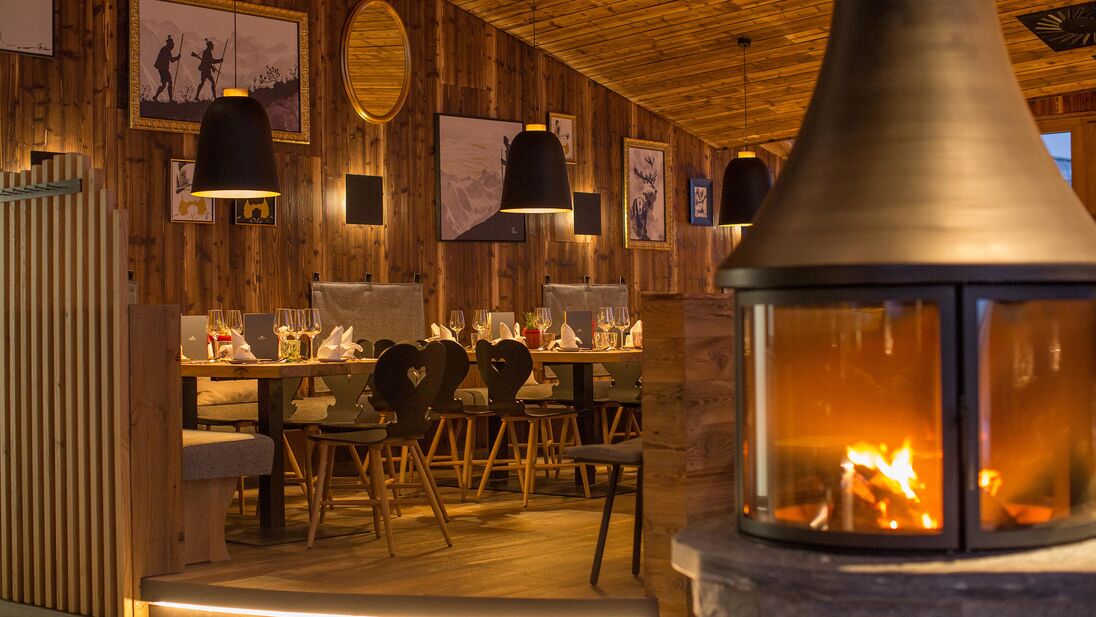 Interior view of the mountain restaurant with wooden decor and fireplace. | © Schmittenhöhebahn AG/Nikolaus Faistauer Photography