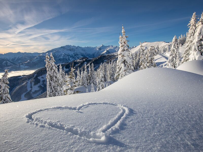 Verschneite Berge mit einem Herz im Schnee im Vordergrund. | © Schmittenhöhebahn AG/Nikolaus Faistauer Photography