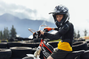 Kind auf E-Motorrad mit Schutzkleidung und Helm im E-Motocross Park. | © Schmittenhöhebahn AG