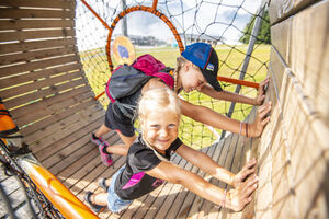 Zwei Kinder spielen und lachen in einem Holzspielgerät. | © Max Steinbauer