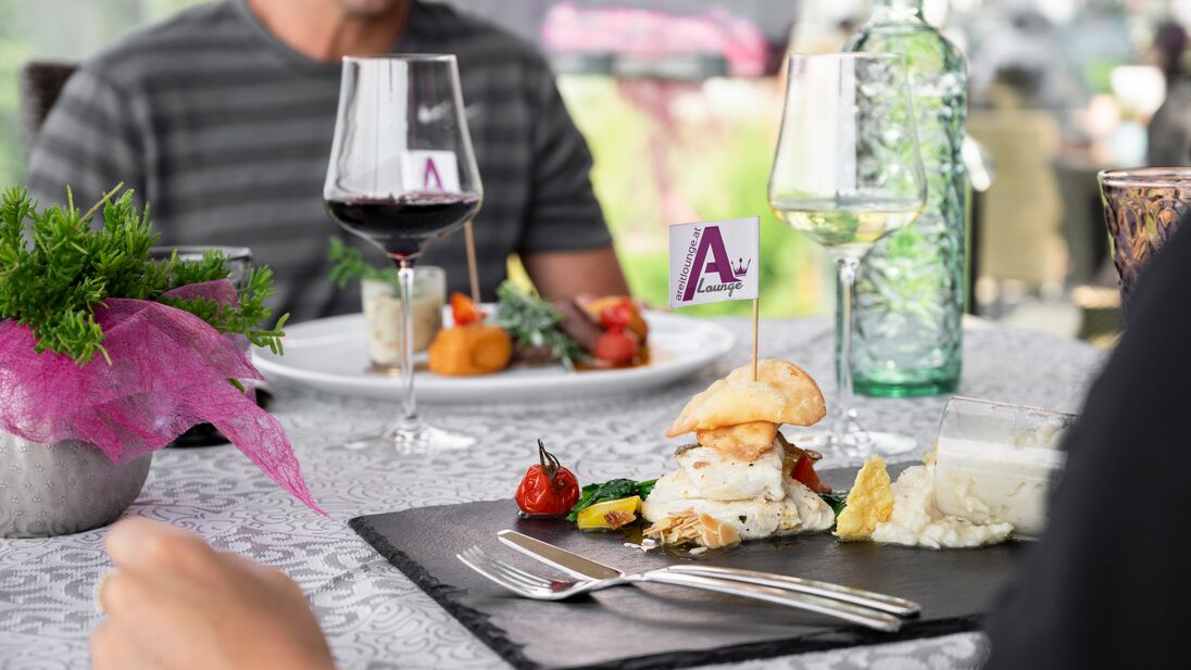 A table with gourmet dishes and wine at the AreitLounge. | © Schmittenhöhebahn AG/Punkt&Komma