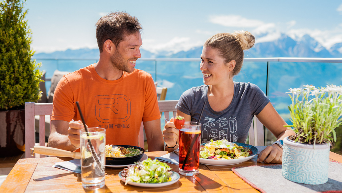 Couple enjoys a meal at the mountain restaurant Franzl with a view of the mountains. | © mr-offenblende.at
