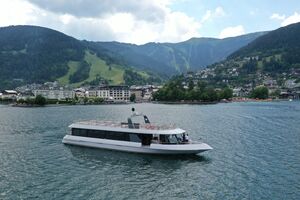 Ein modernes Boot auf dem Zeller See mit Bergen und Stadt im Hintergrund. | © Schmittenhöhebahn AG