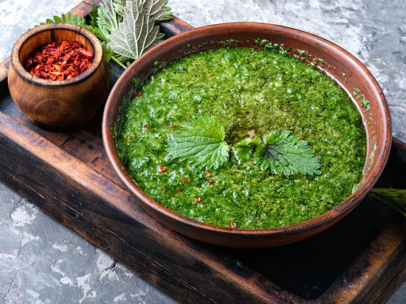 Eine grüne Kräutersauce in einer Schüssel, serviert mit roten Chiliflocken.