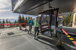 Zwei Wanderer steigen in eine Gondel an einer Bergstation auf der Schmittenhöhe. | © FotoAtelier Faistauer