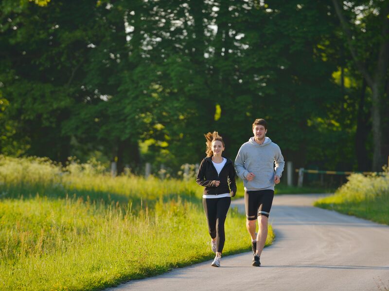 Ein Mann und eine Frau joggen auf einem Weg im Park. | © Benis Arapovic