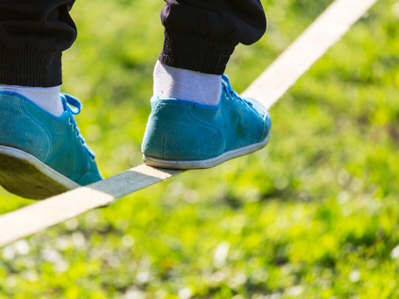 Person balanciert in blauen Schuhen auf einem Seil im Freien. | © Galyna Andrushko