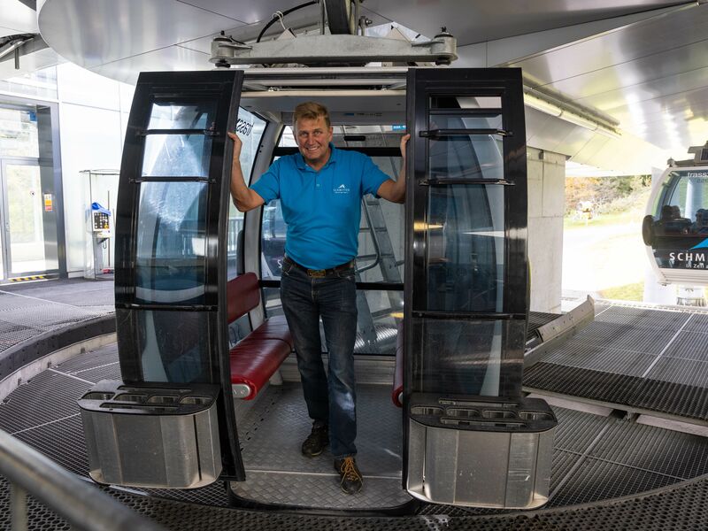 Ein Mann in blauer Uniform betritt eine Gondel der Schmittenhöhebahn. | © Schmittenhöhebahn AG