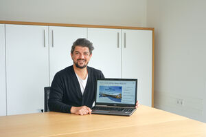 Mann am Tisch mit Laptop, zeigt Kulinarische Winter News 2021/22. | © Schmittenhöhebahn AG