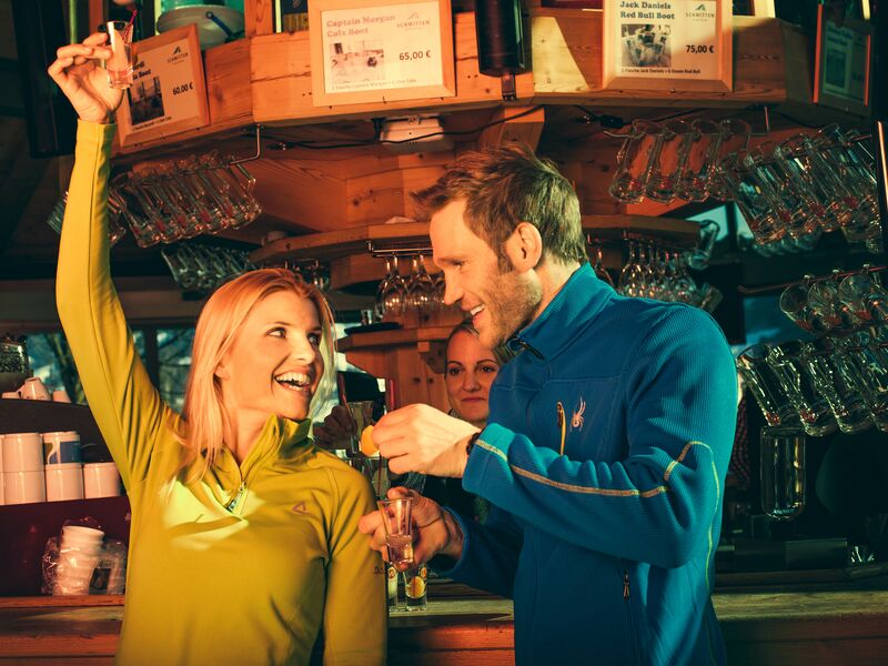 Ein Mann und eine Frau stoßen an einer Bar fröhlich an. | © Schmittenhöhe