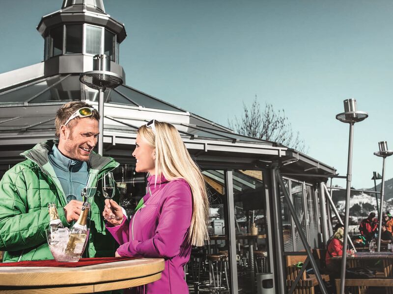 Ein Paar genießt Wein im winterlichen Außenbereich eines Cafés. | © Schmittenhöhe
