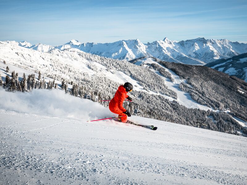 Skifahrer in rotem Anzug fährt die Piste hinunter. | © Bründl Sports