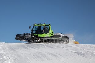Grüne Pistenraupe glättet schneebedeckte Piste. | © Nikolaus Faistauer Photography